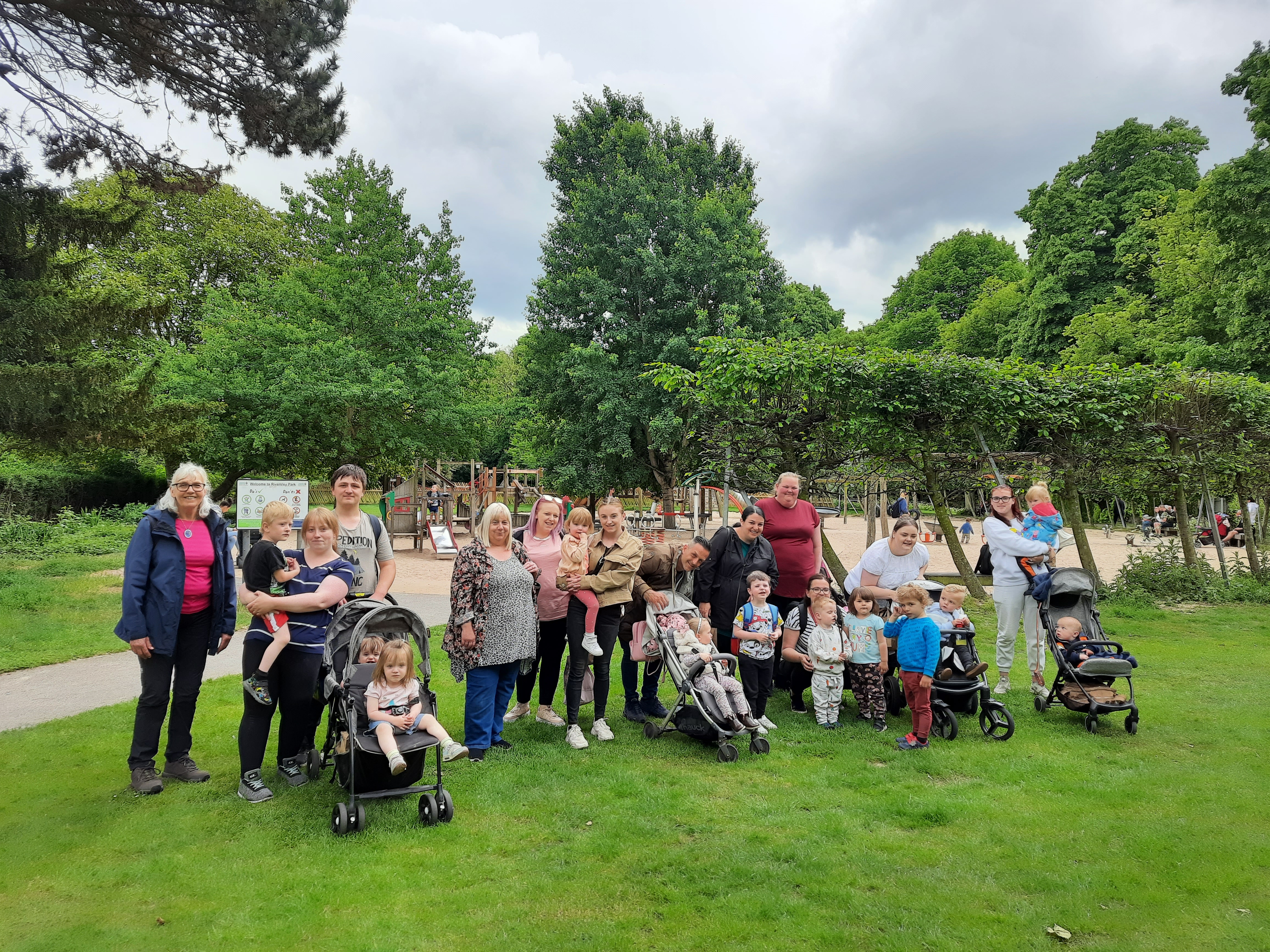 A group of families pose for the camera in a park