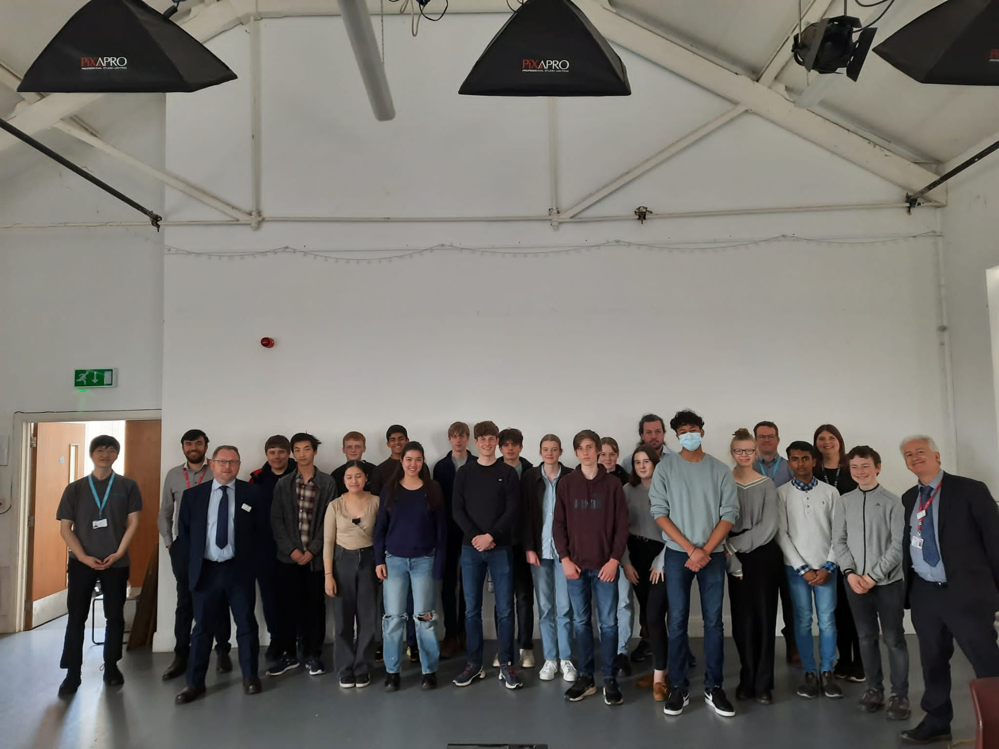 Photo of a mixed group of people in front of a blank white wall.