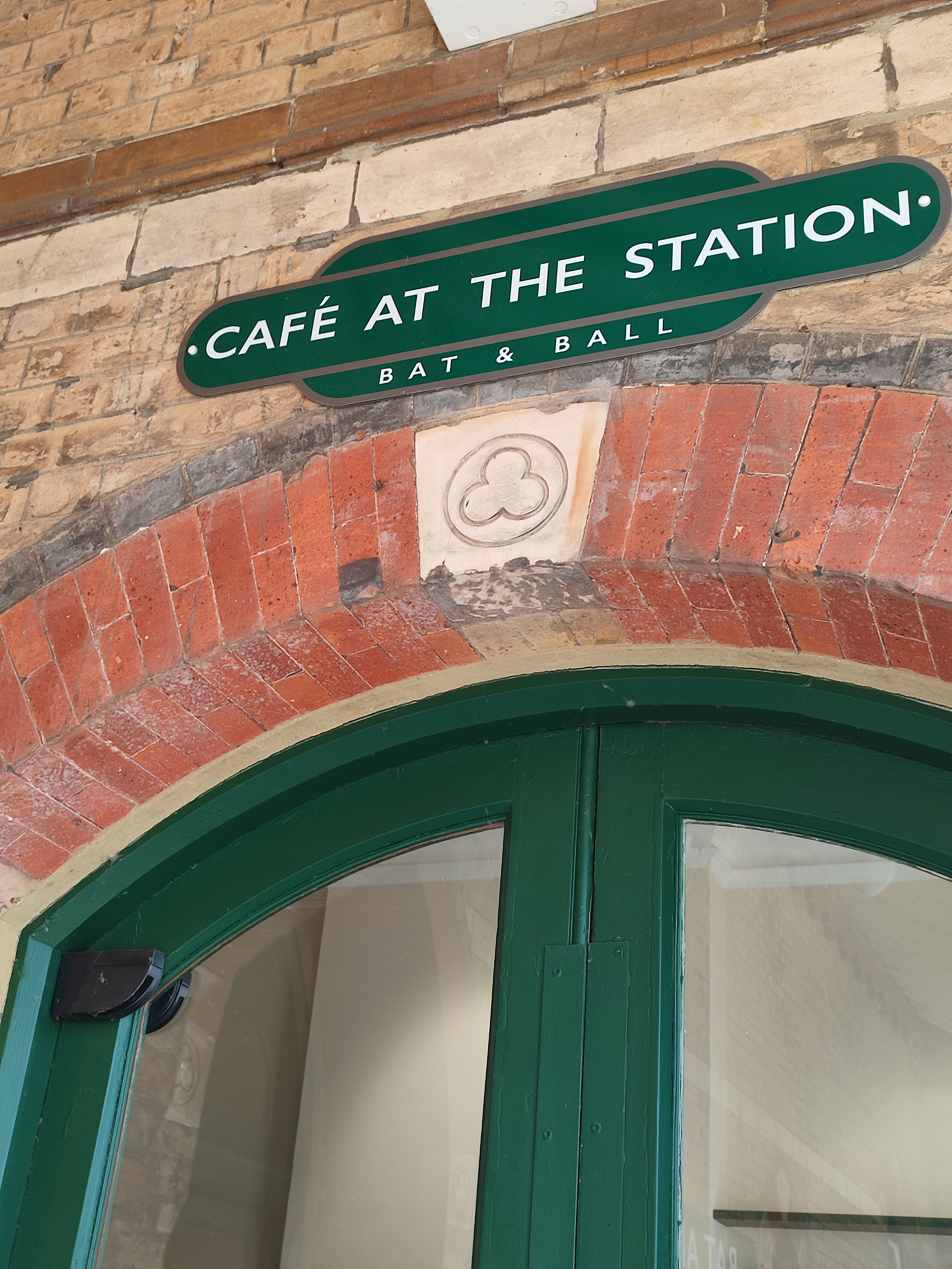 Green sign with Cafe at the station at the top of a brick archway.