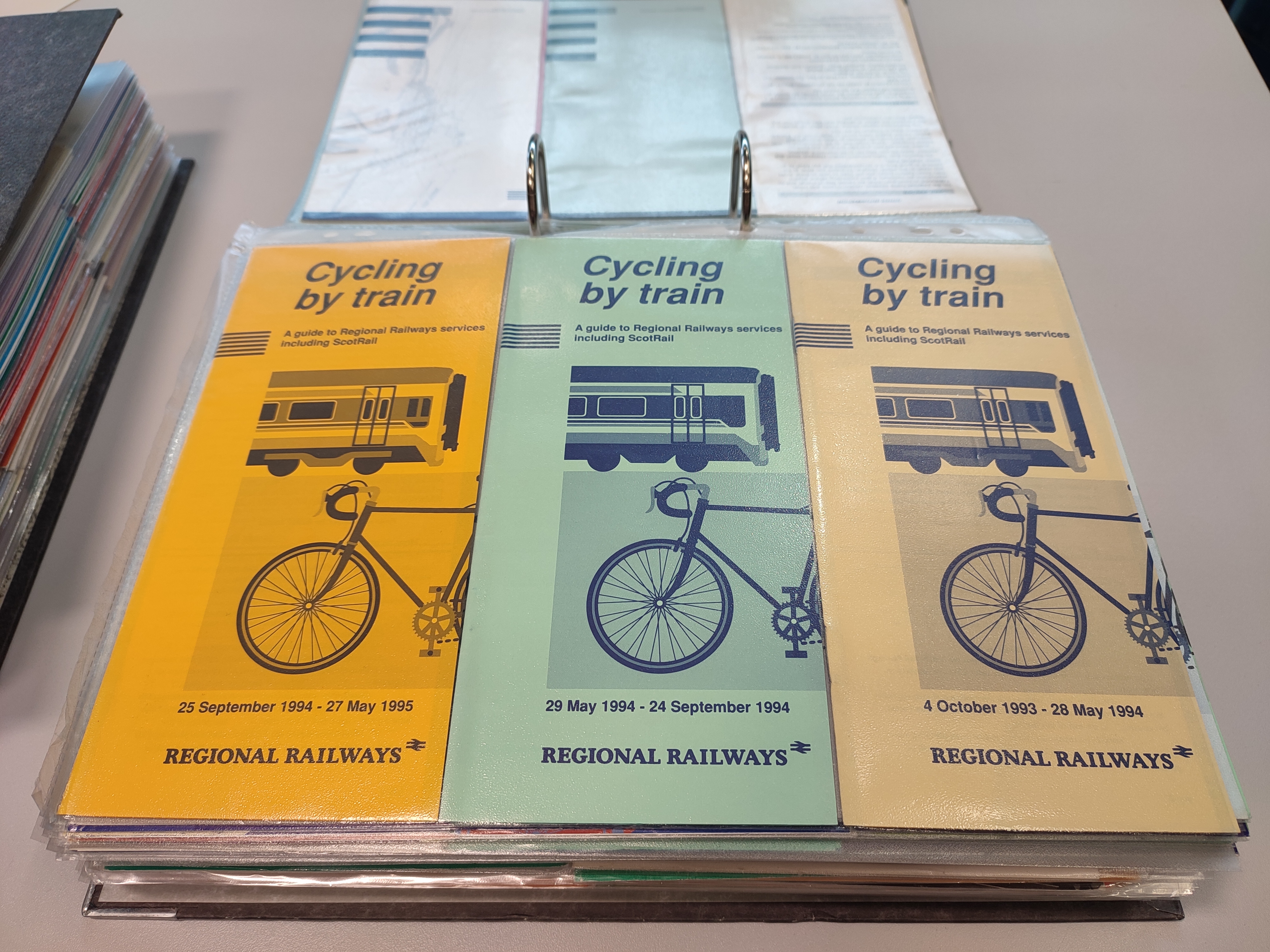 3 leaflets in green, orange and pale orange with a bike and a train on the front.